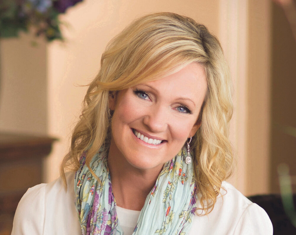 Bilde av forfatter Karen Kingsbury. Hun smiler og er ikledd hvit bluse og et turkis skjerf